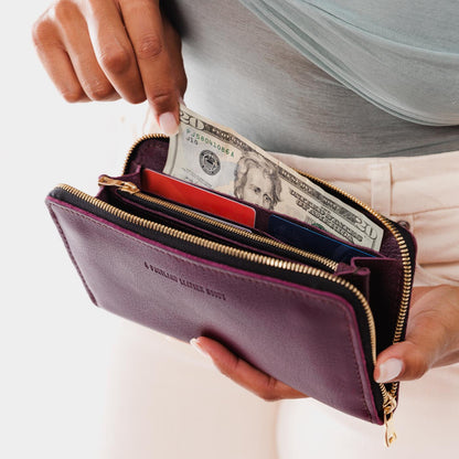 Plum | Model holding large accordion leather wallet with zipper open