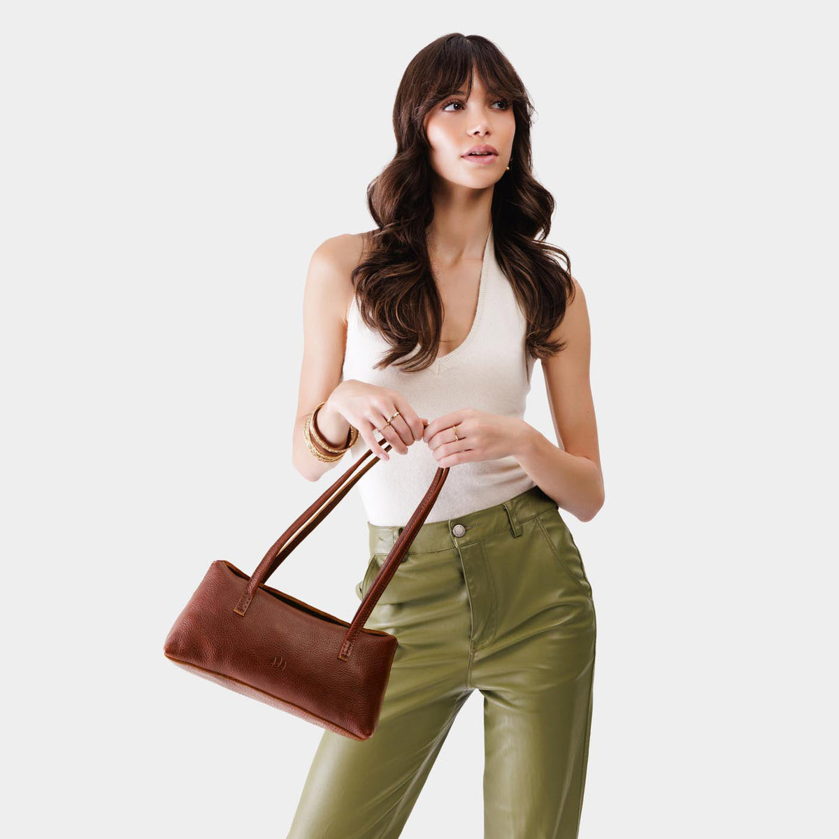 Nutmeg | Woman wearing a light brown leather bowler bag against a white background