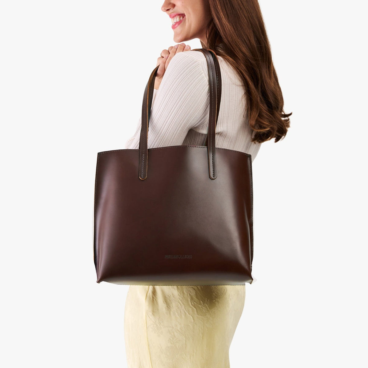 Chocolate Brown*Medium | Model holding leather tote bag with interior snap key loop
