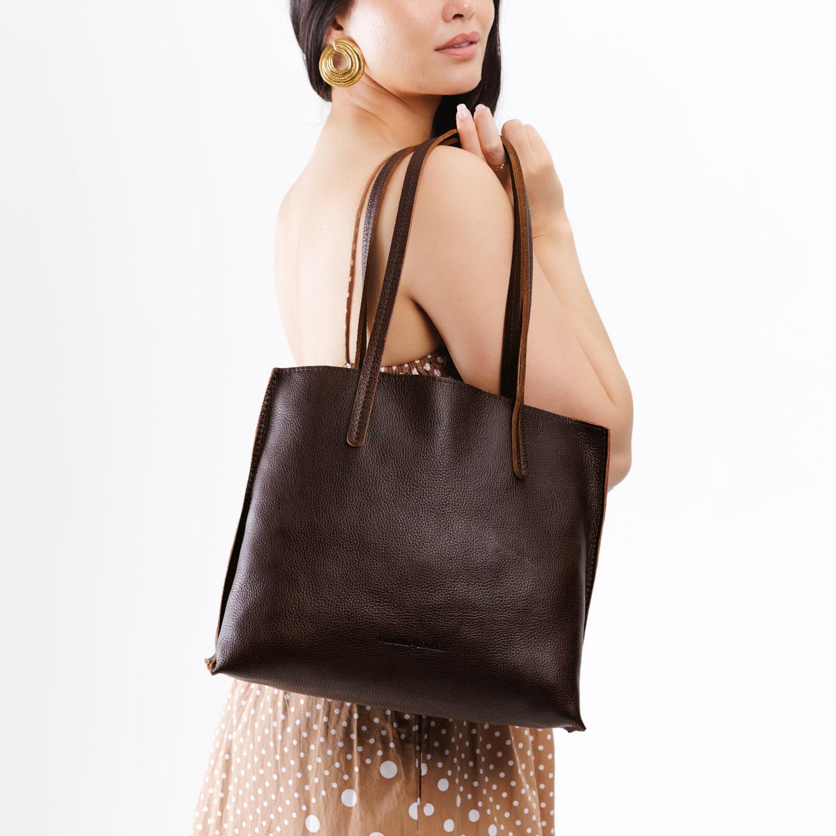 Coldbrew*Medium | Model holding leather tote bag with interior snap key loop