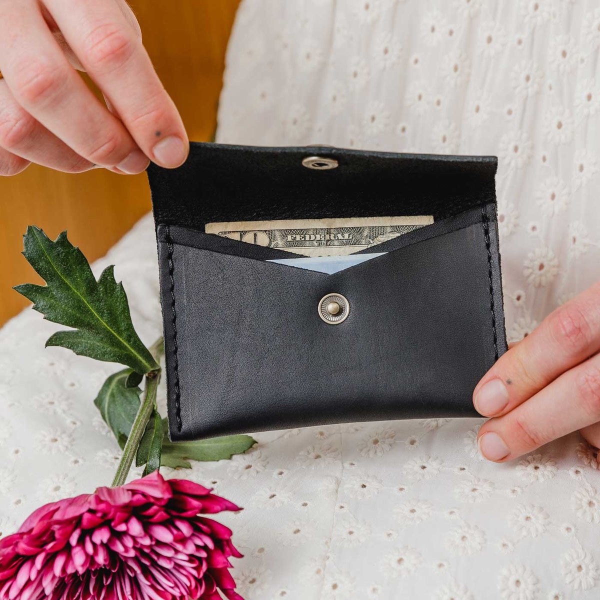 Black | Model holding small leather envelope wallet with snap closure open