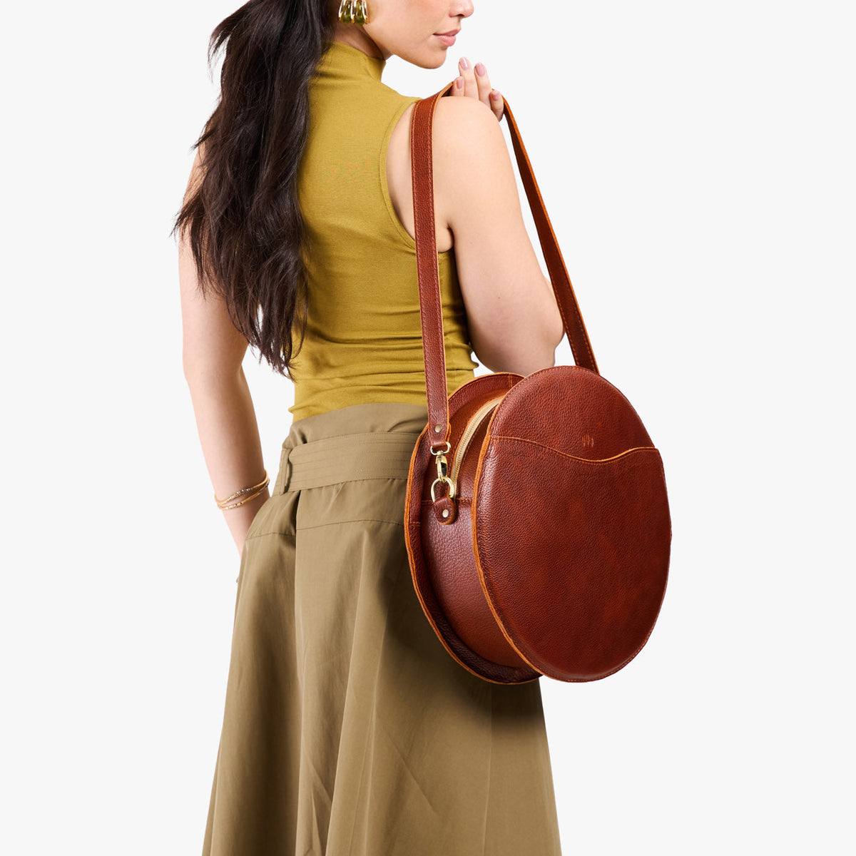 Nutmeg | Model carrying large circle shaped leather bag with top zipper and carrying strap