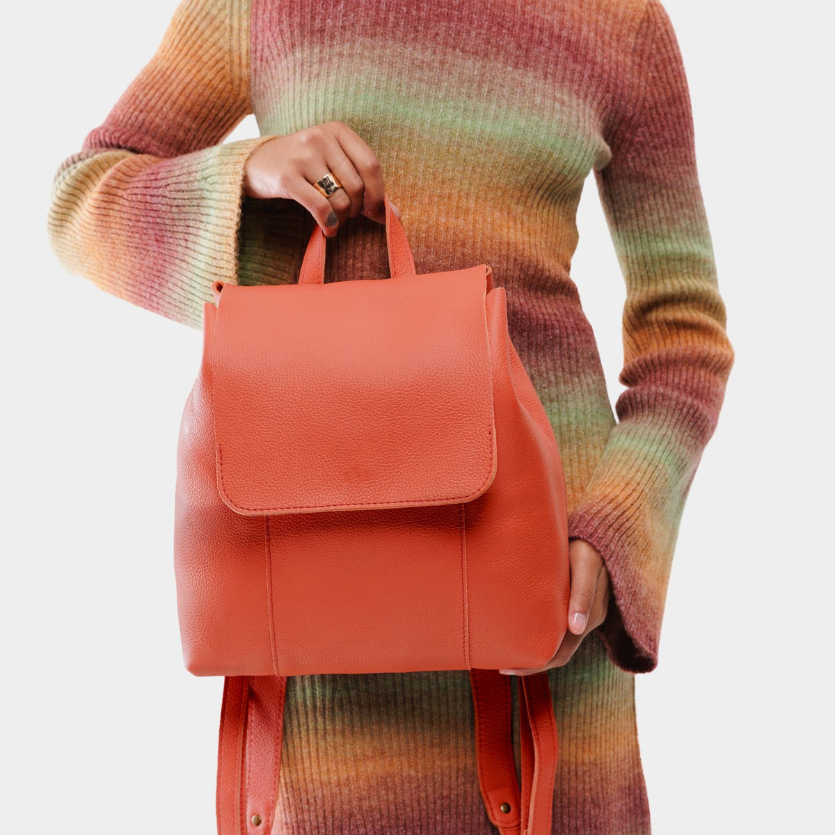 Coral | Model wearing a leather backpack on a white background