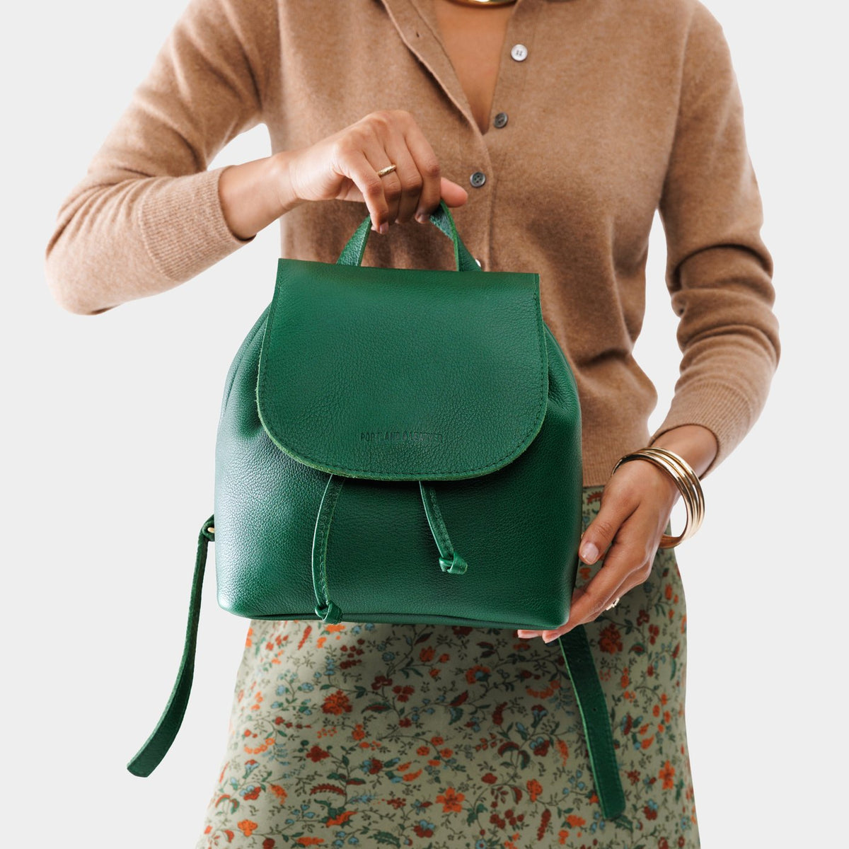 Bacalar | Pebbled green leather drawstring backpack being held by a person wearing a brown sweater.