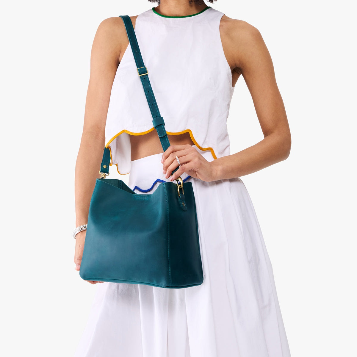 Westward Blue | Model wearing symmetrical bucket bag with latch closure and removable crossbody strap