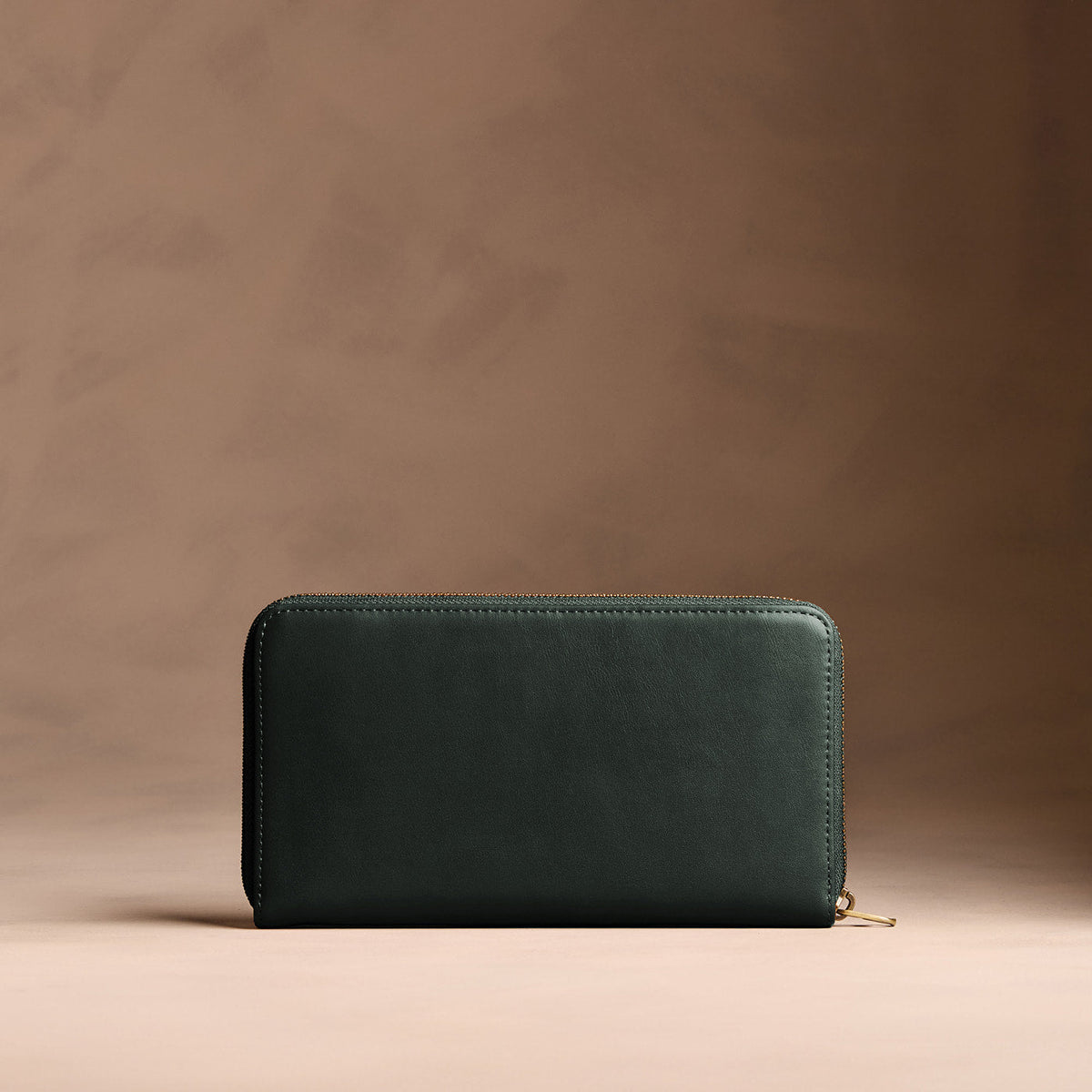 Regent Green | Full zip around wallet with a strap on a brown background