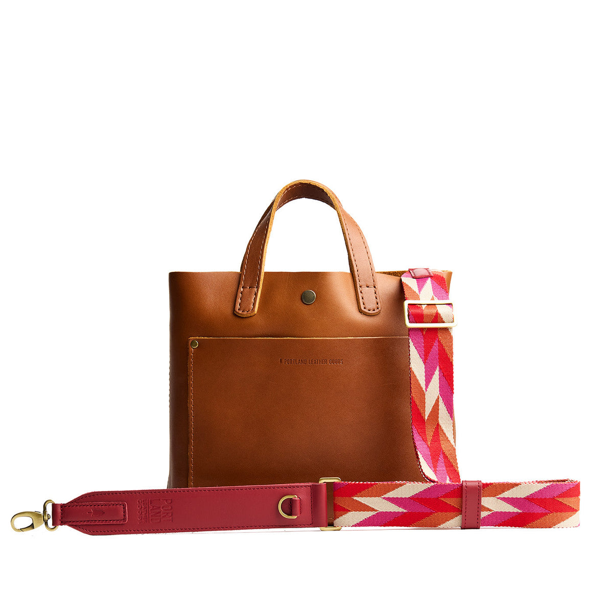 Tropical Punch | Patterned fabric and leather strap attached to leather purse on a white background