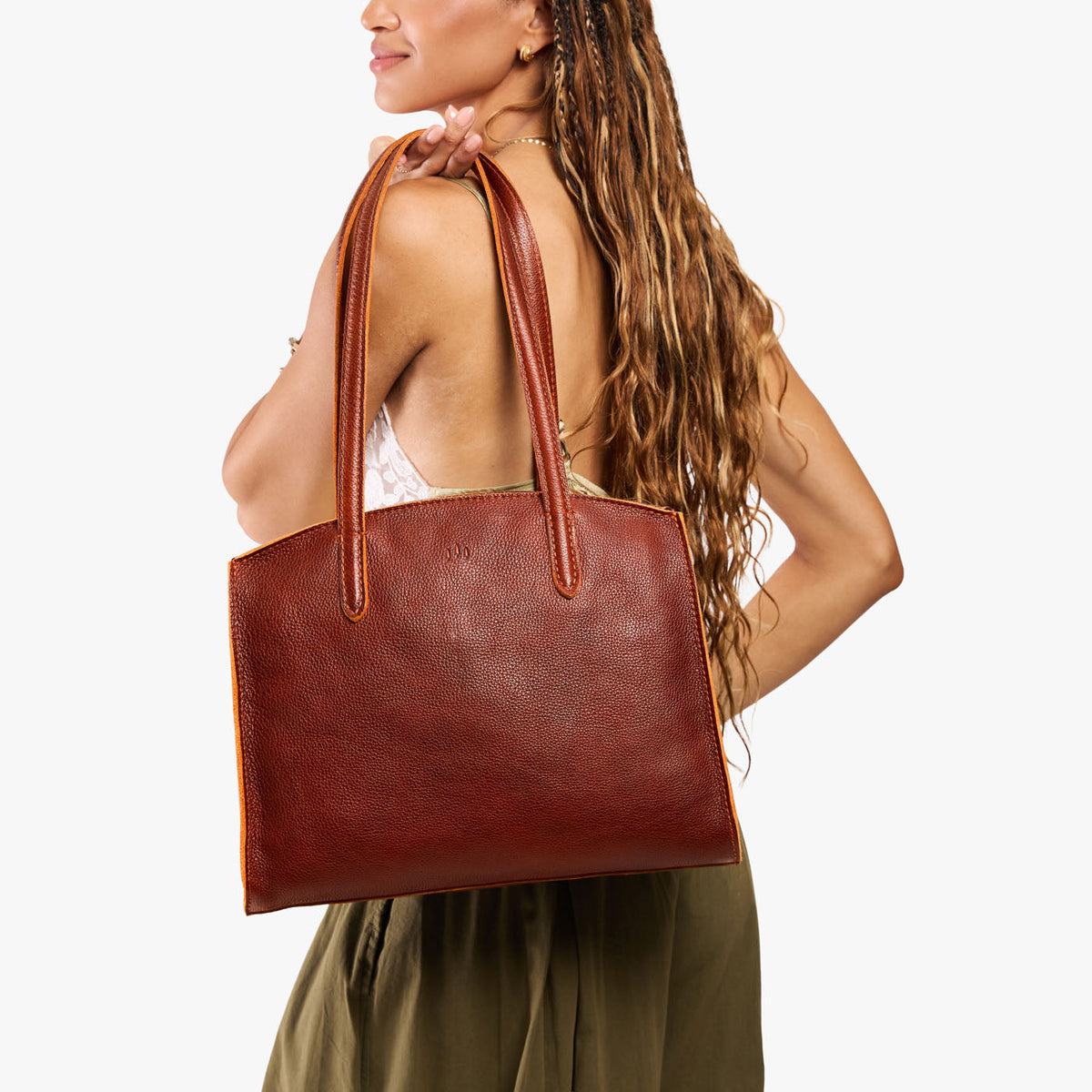 Nutmeg*Large | Model carrying leather tote bag with handles, adjustable crossbody strap, and two back pockets