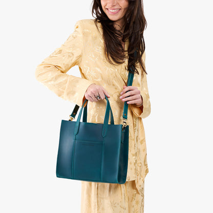 Westward Blue | Model holding structured mid-size tote bag with overlapping panels and crossbody strap