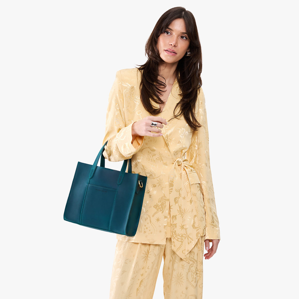 Westward Blue | Model holding structured mid-size tote bag with overlapping panels and crossbody strap