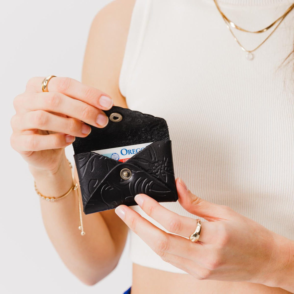 Dahlia | Model holding small leather wallet with scalloped edge open