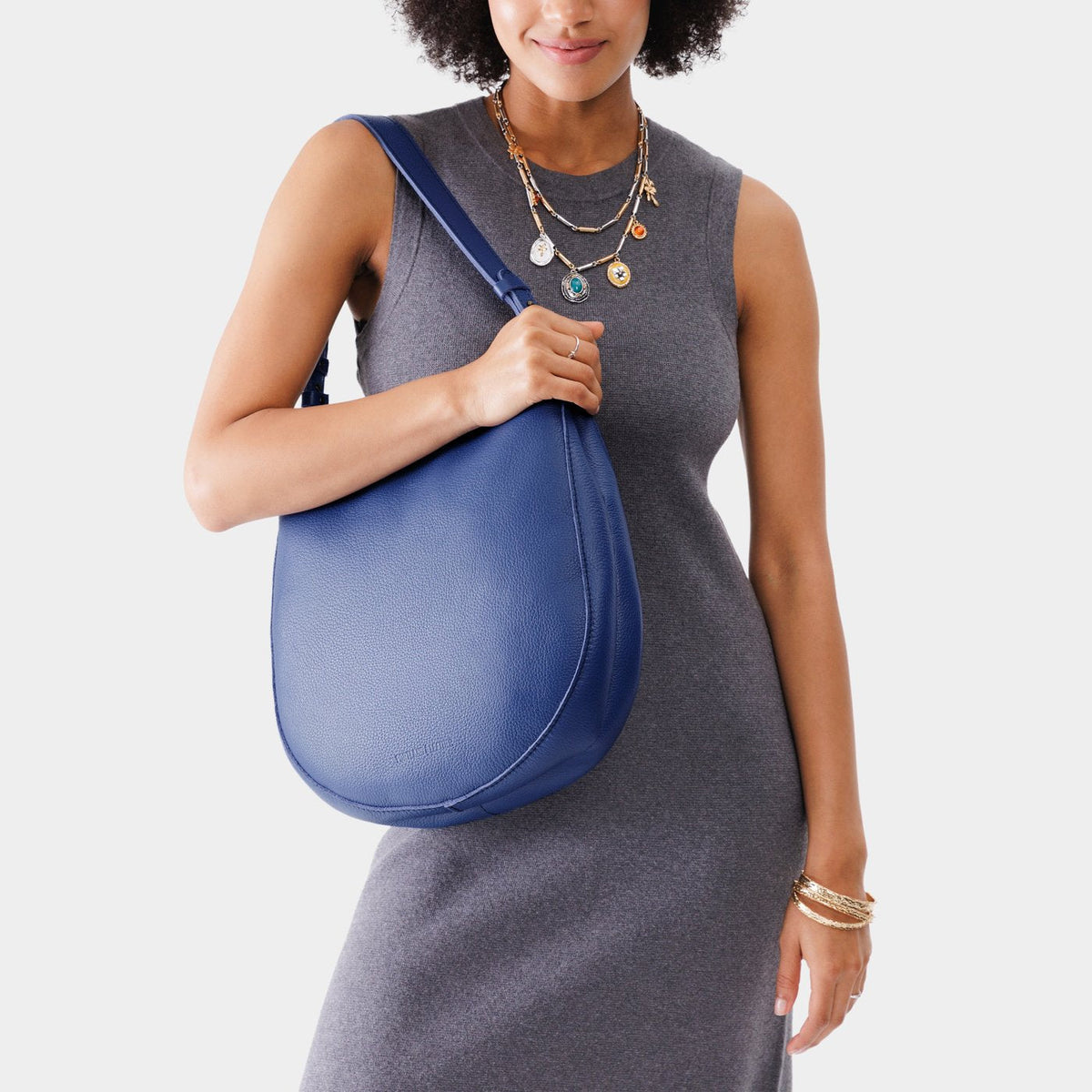 Molino Blue*Large | Woman wearing rounded shoulder bag with adjustable strap on a white background