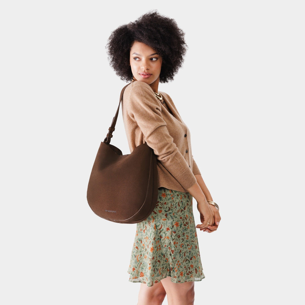 Stagecoach*Large | Woman wearing rounded shoulder bag with adjustable strap on a white background