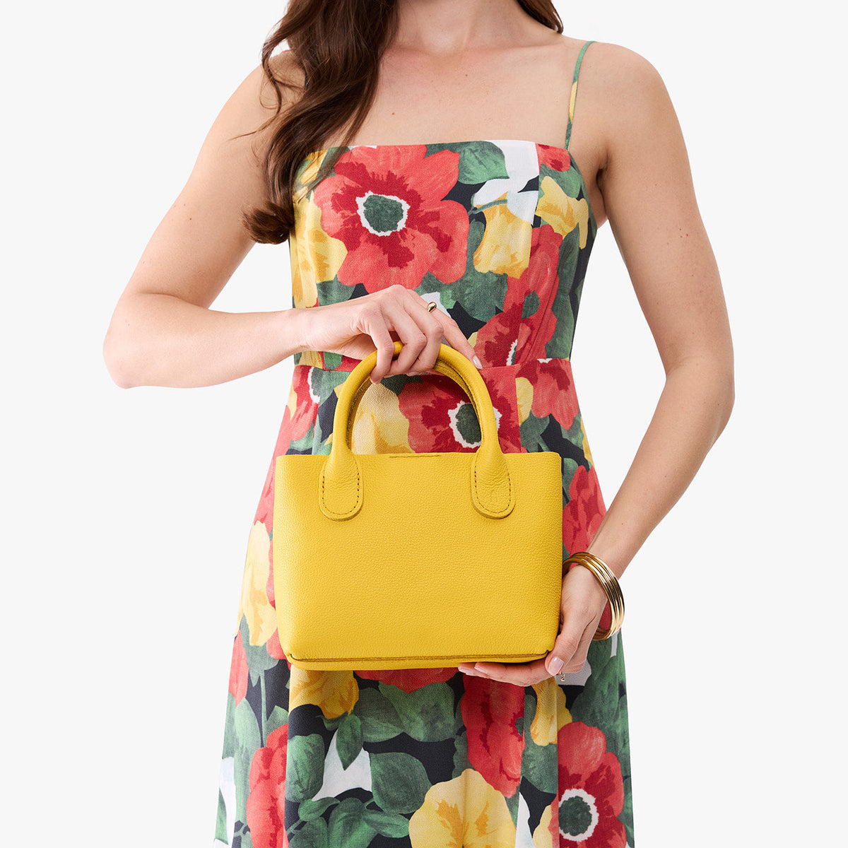 Canary*Small | Model holding a petite tote purse with structured leather handles and crossbody strap