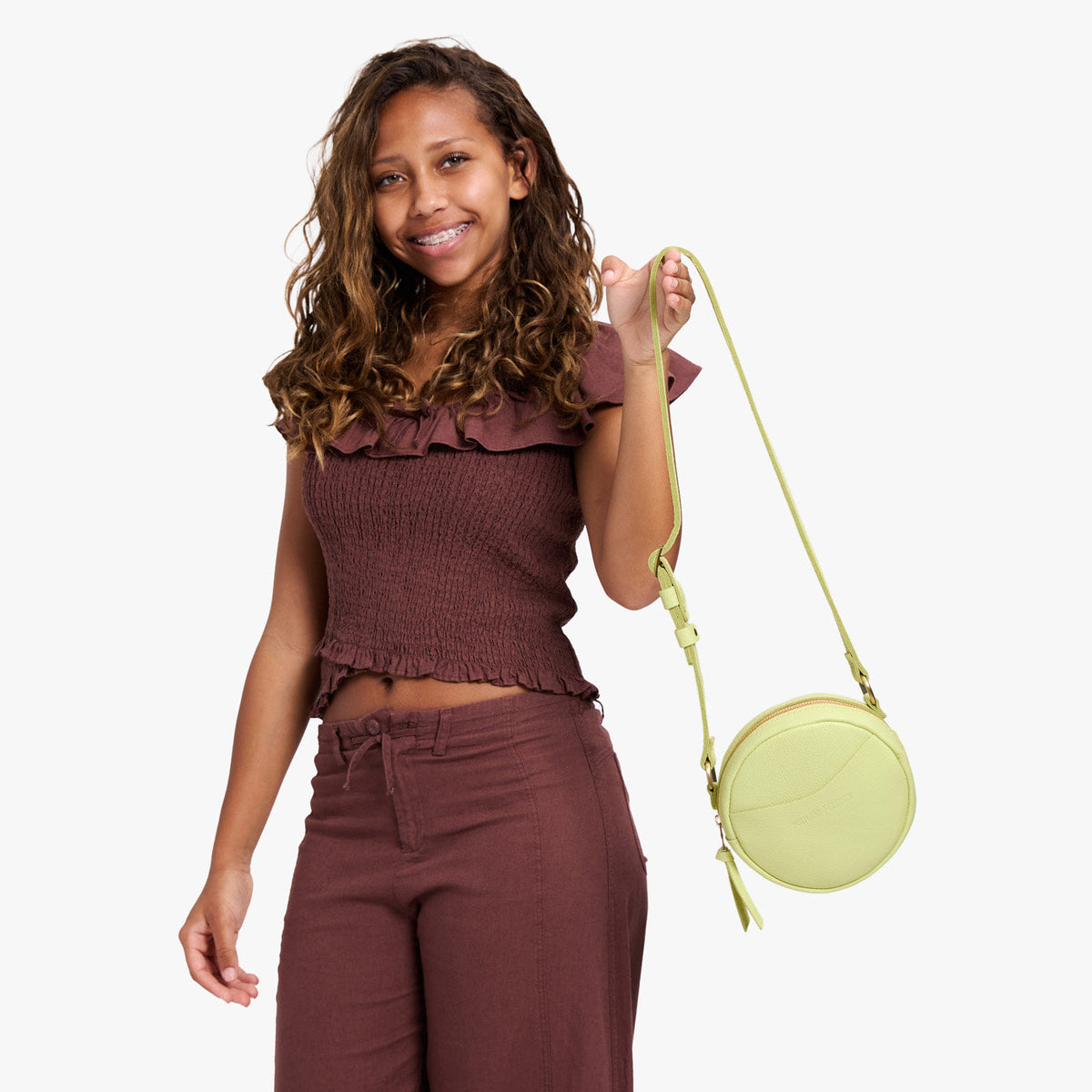 Shadow Lime | Model holding a circle shaped crossbody bag with top zipper and gold accents