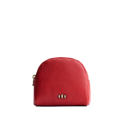 Ruby | Curved top leather pouch with zipper opening, flat base, and three metal tree emblems in front